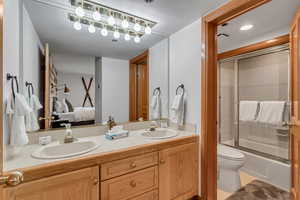 Bathroom with double vanity, ensuite bathroom, and bath / shower combo with glass door