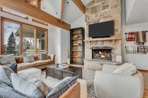Living room with a fireplace, wood finished floors, and wood ceiling