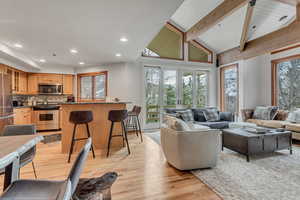 Living room with light wood-style floors, beam ceiling, recessed lighting, and high vaulted ceiling