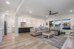 Living room featuring a ceiling fan, recessed lighting, light wood finished floors, arched walkways, and a chandelier