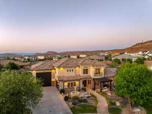 Mediterranean / spanish-style home featuring stone siding, a tile roof, driveway, stucco siding, and a pergola
