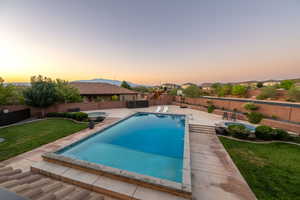 Pool at dusk featuring a fenced backyard, an outdoor hot tub, a patio, and a mountain view