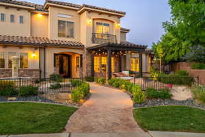 Mediterranean / spanish-style home with a tile roof, a balcony, stucco siding, stone siding, and a pergola