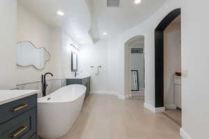Full bath featuring vanity, a freestanding bath, recessed lighting, and tile patterned floors