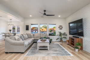 Living area featuring ceiling fan, recessed lighting, light wood-type flooring, a chandelier, and arched walkways