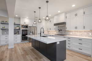 Kitchen with stainless steel appliances, open shelves, backsplash, white cabinets, and recessed lighting