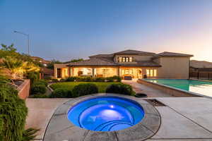 Rear view of property with an in-ground hot tub, an outdoor pool, a tile roof, stucco siding, and a patio area