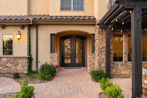 Property entrance featuring french doors, stone siding, and stucco siding