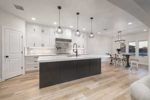 Kitchen featuring tasteful backsplash, white cabinetry, light wood-style floors, and recessed lighting