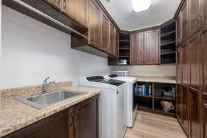 Laundry area featuring independent washer and dryer, light wood-style floors, and cabinet space
