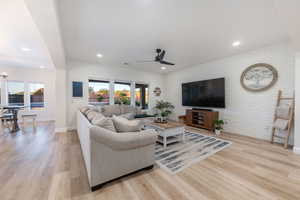 Living area featuring a ceiling fan, brick wall, wood finished floors, and recessed lighting