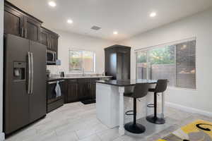 Kitchen with appliances with stainless steel finishes, a kitchen bar, healthy amount of natural light, a kitchen island, and recessed lighting