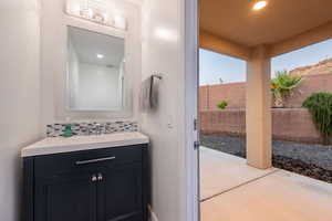 Bathroom with vanity, decorative backsplash, and recessed lighting