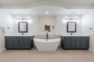 Bathroom featuring two vanities, a soaking tub, tile patterned flooring, and recessed lighting