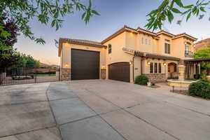 Mediterranean / spanish home featuring stone siding, driveway, stucco siding, a gate, and a tiled roof