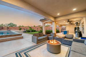 Fenced backyard with a patio area, a ceiling fan, and an outdoor living space with a fire pit