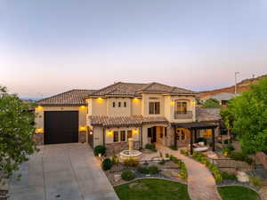 Mediterranean / spanish-style home with stone siding, driveway, a balcony, a tile roof, and stucco siding