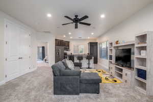 Living area featuring a ceiling fan, light carpet, and recessed lighting