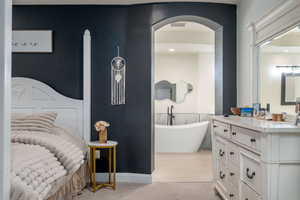 Bedroom with light colored carpet and arched walkways