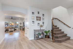 Stairs featuring wood finished floors, arched walkways, and a ceiling fan
