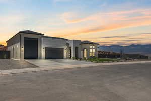 Contemporary house with an attached garage, a mountain view, driveway, and stucco siding