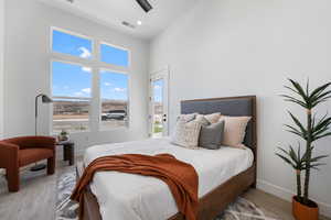 Bedroom with wood finished floors, a high ceiling, and a ceiling fan