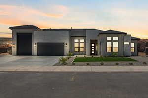 Contemporary house featuring a garage, a front lawn, concrete driveway, stucco siding, and a tiled roof