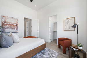 Bedroom featuring light wood finished floors, a walk in closet, a towering ceiling, and a closet