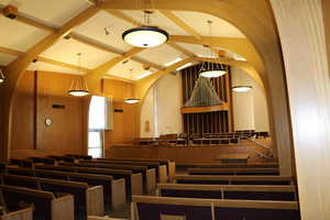 Chapel with musical organ, dais with fixed seats, and fixed upholstered pews