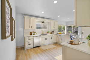 Kitchen with stainless steel dishwasher, backsplash, light countertops, light wood-style flooring, and recessed lighting