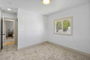 Carpeted spare room featuring attic access and a smoke detector