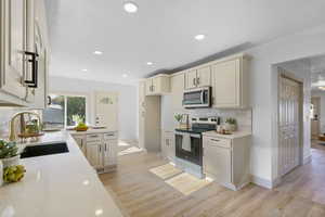 Kitchen featuring stainless steel appliances, light wood finished floors, light countertops, backsplash, and recessed lighting