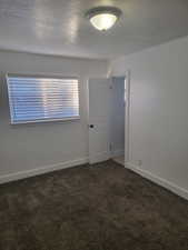 Carpeted spare room with baseboards and a textured ceiling