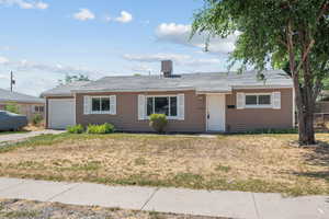 Ranch-style home with a garage, driveway, and a front lawn