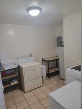 Laundry area with washer / clothes dryer, a textured ceiling, light tile patterned floors, water heater, and electric panel