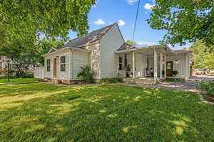 View of front of home with covered porch, a front lawn, and roof with shingles