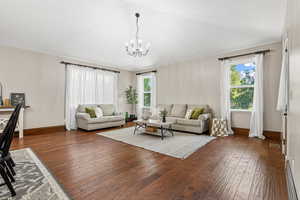 Living room with a chandelier and dark wood-type flooring