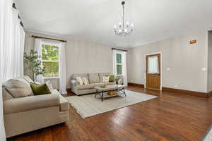 Living room with a chandelier, hardwood / wood-style flooring, and healthy amount of natural light