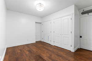 Unfurnished bedroom with multiple closets, dark wood-type flooring, and a textured ceiling