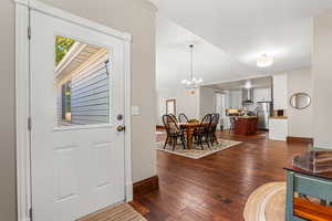 Foyer entrance featuring dark wood-style flooring, lofted ceiling, and a chandelier