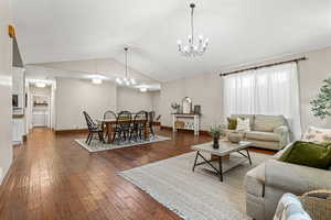 Living room featuring  a chandelier, Vaulted ceiling, and dark wood-type flooring