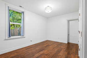 Unfurnished room with dark wood-style floors and baseboards