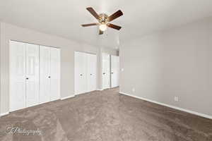 Unfurnished bedroom featuring two closets, carpet flooring, and ceiling fan