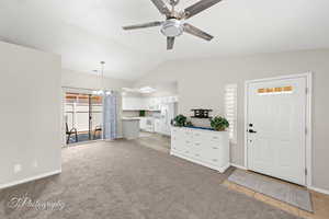 Living room featuring lofted ceiling, a ceiling fan, light carpet, and a chandelier