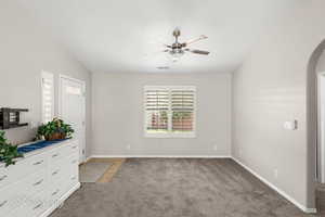 Unfurnished bedroom with light colored carpet, vaulted ceiling, and a ceiling fan