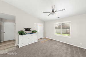 Unfurnished bedroom with light carpet, vaulted ceiling, and ceiling fan