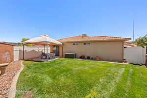 Rear view of property with stucco siding, a tile roof, a fenced backyard, and a patio area