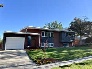Tri-level home featuring brick siding, an attached garage, and concrete driveway