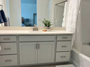 Ensuite bathroom featuring vanity, shower / bathtub combination with curtain, and tile patterned flooring