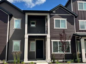 View of front of property with a balcony, a front lawn, and board and batten siding